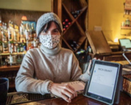 Woman with a face mask sitting next to a laptop